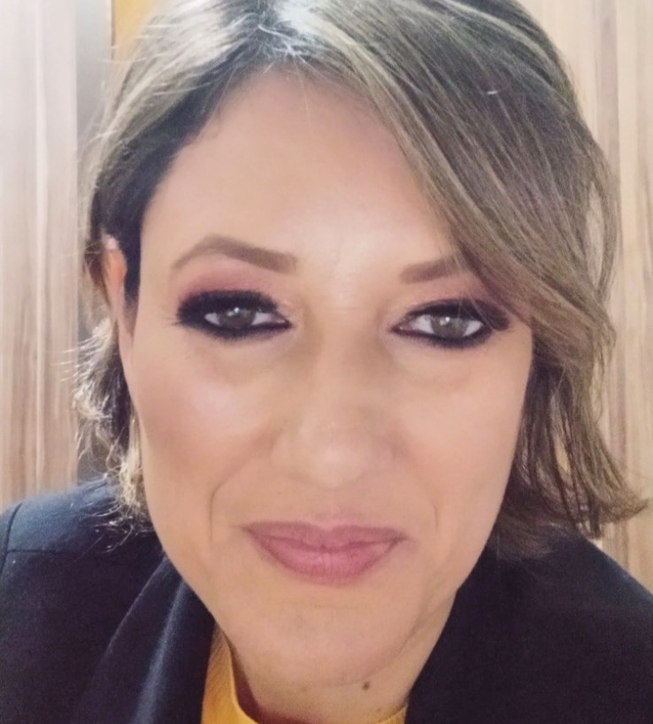 foto de Regiane Travensolo, com cabelos longos e escuros, sorrindo e olhando diretamente para a câmera.